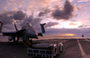The Sun Rises Behind An F/a-18  Hornet  Strike Fighter Aircraft Parked And Secured On The Ship S Flight Deck. Image
