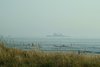 As Virginia Beach Surfers Catch The Morning Beach Break, A Norfolk-based U.s. Navy Warship Returns Home Image