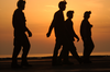 Crewmembers Walk Across The Ship S Flight Deck Before The Sun Sets Over The Arabian Sea. Image